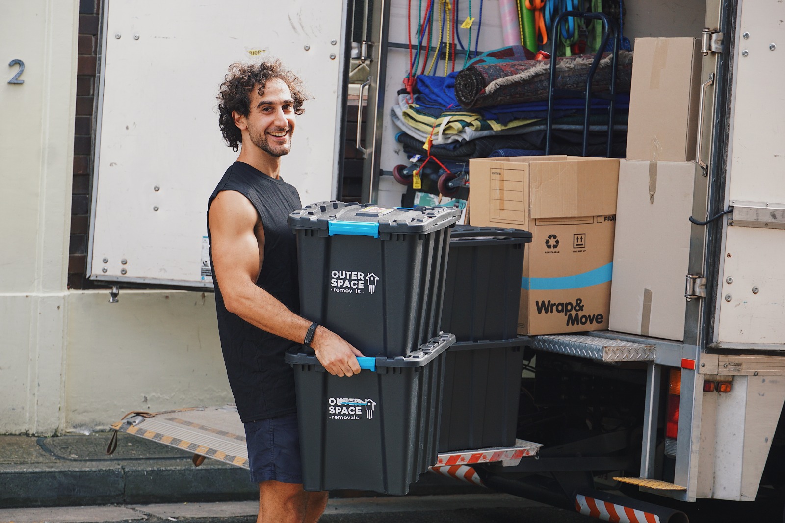 Smiling mover carrying two crates to the truck