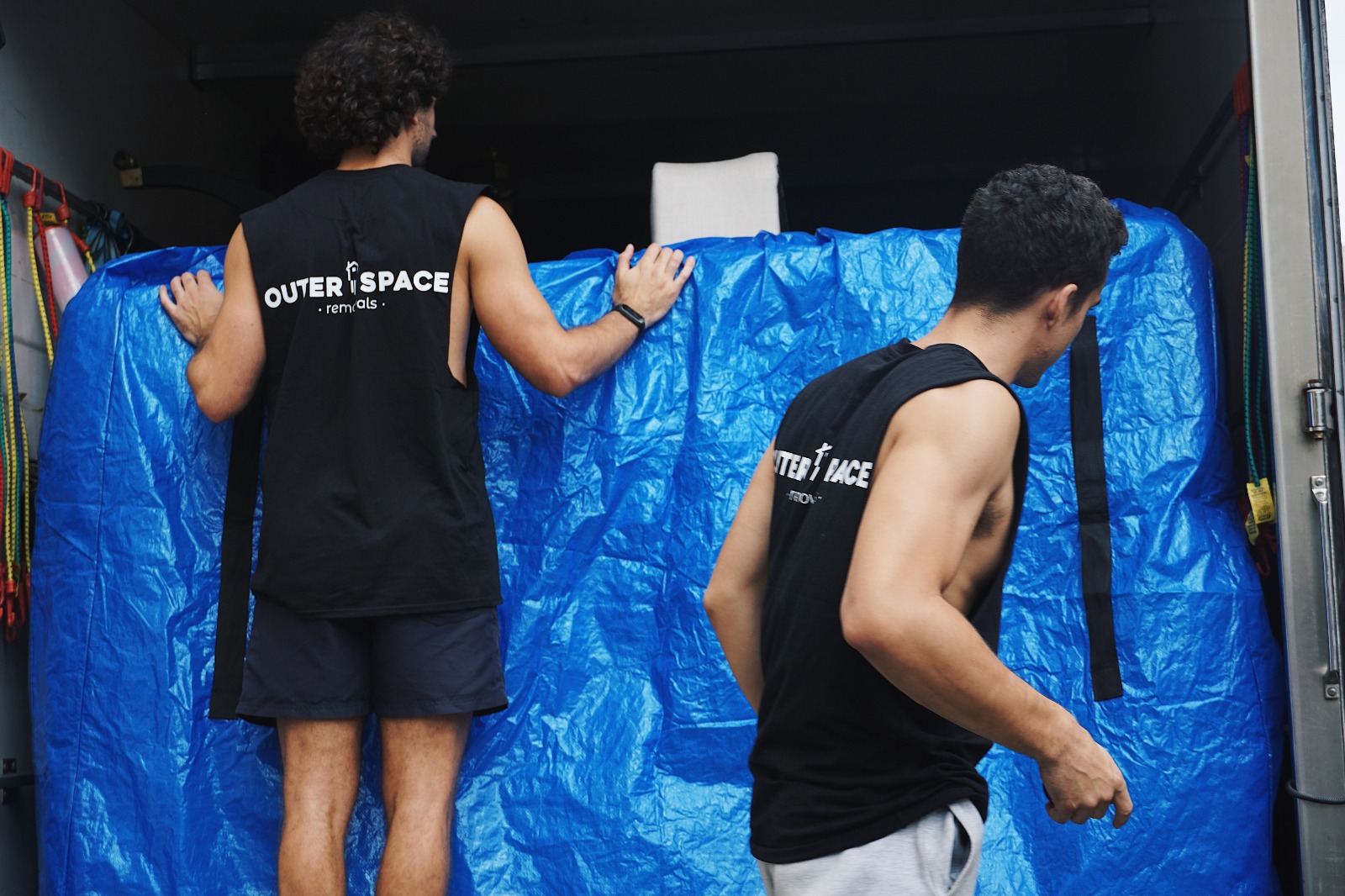 Movers securing a wrapped item inside the truck