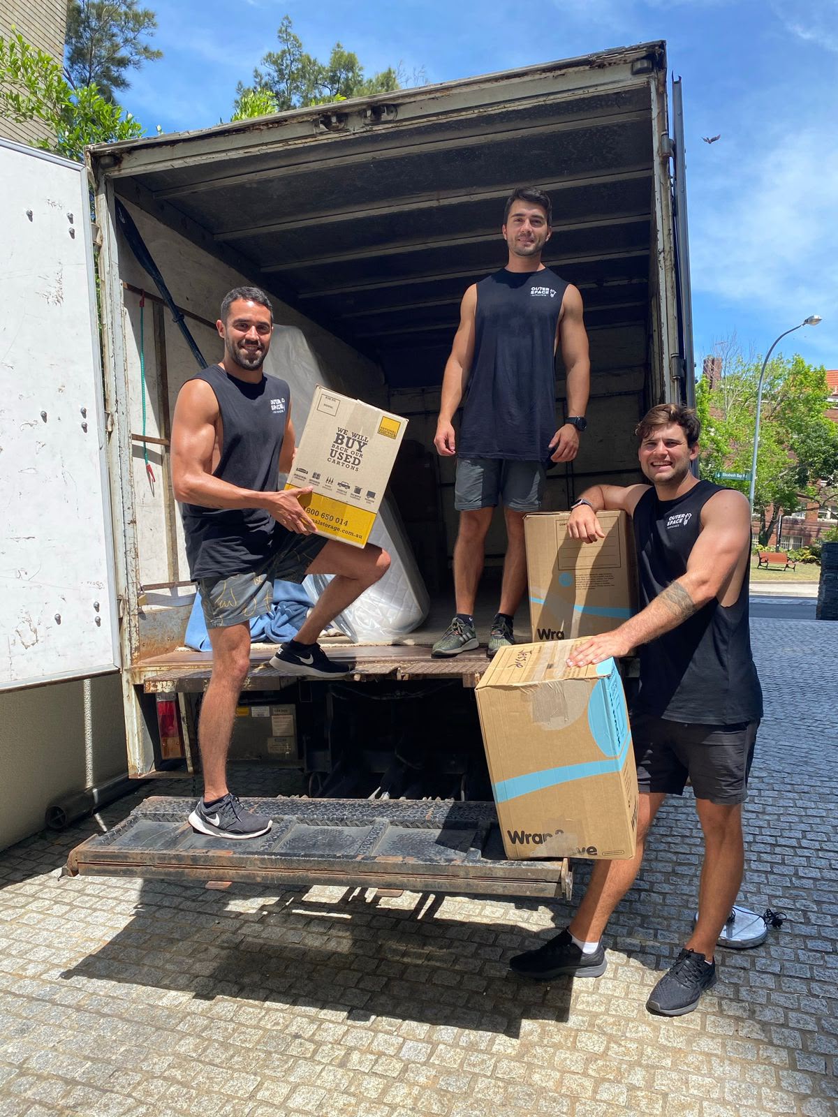 Outer Space Removals team members loading moving boxes into the truck on a sunny Sydney day